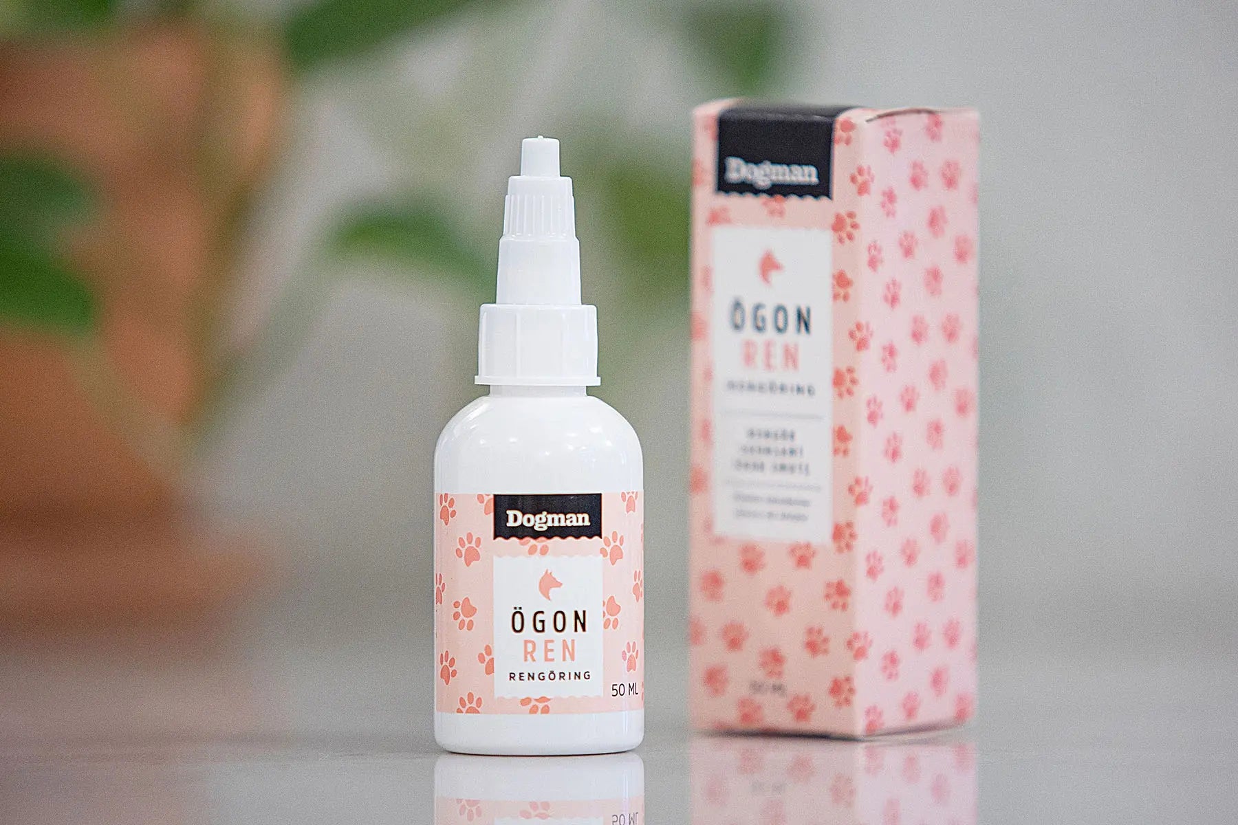 En pakke og en flaske Dogman Øyerens til hund på en benk med en plante i bakgrunnen.