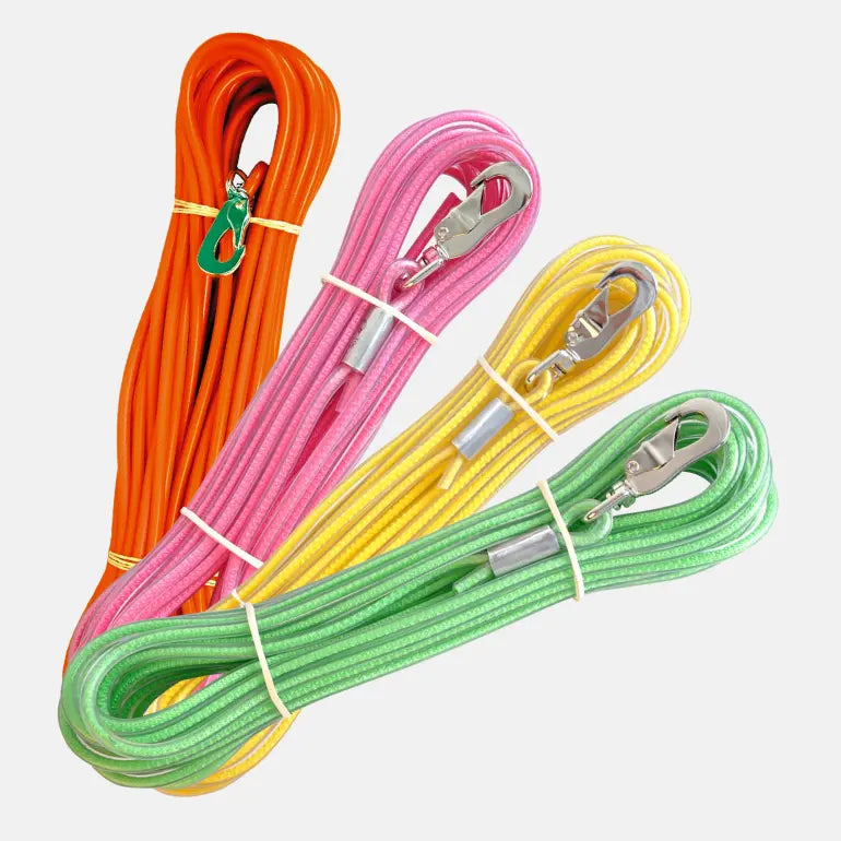 Gummiert Sporline fra Alac Dogman i fire farger: orange, rosa, gul og grønn på grå bakgrunn.