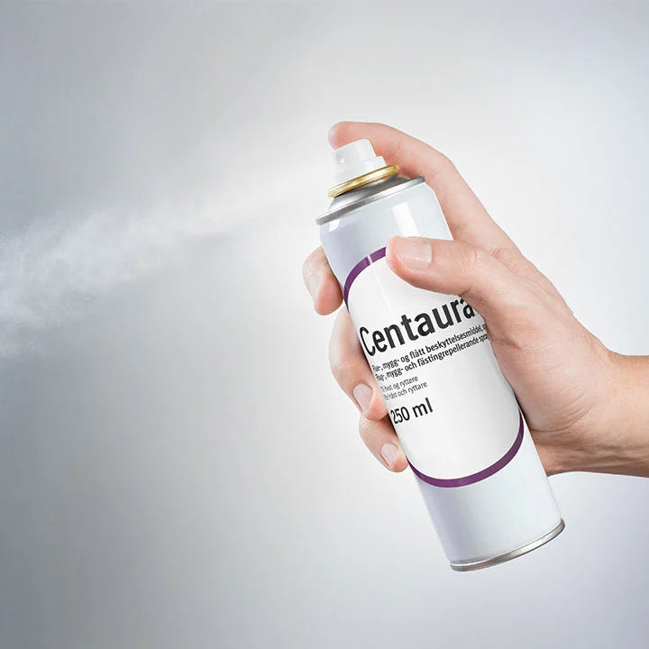 Centaura insektspray for hund, hest og menneske sprayes ut i luften mot grå bakgrunn.